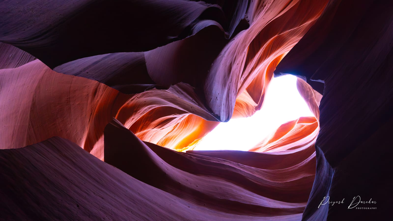 Sculpted sandstone walls inside Lower Antelope Canyon curving around a bright shaft of daylight above.